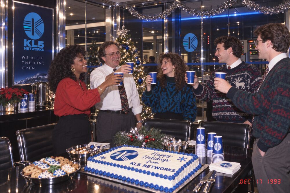 Colleagues raising cups beside a decorated cake